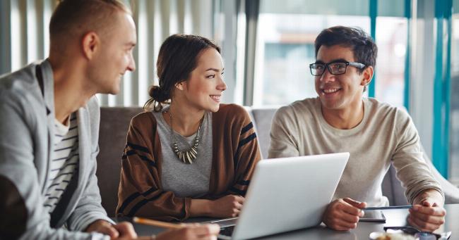 Một nhóm người đang trao đổi và mỉm cười với nhau trong một môi trường văn phòng hiện đại, biểu lộ sự biết ơn và tinh thần đồng đội